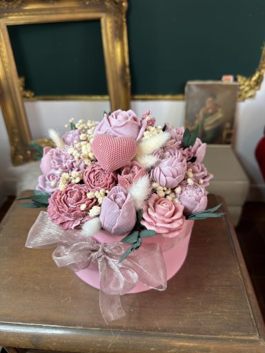 Ein Bouquet aus rosa und lila Blumen in einem pinken Topf, verziert mit Bändern. Sojawachs-Bouquet Rosé