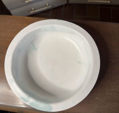 Marble Dream Weiße Schüssel mit grünen Spritzern, auf einer Holzoberfläche platziert.